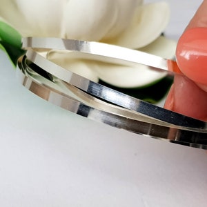 May include: Three silver metal wire rings stacked on top of each other.