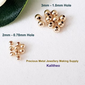 May include: Two groups of gold-colored metal beads. The larger group is 3mm in diameter with a 1.0mm hole. The smaller group is 2mm in diameter with a 0.78mm hole. Precious Metal Jewellery Making Supply Kalitheo.