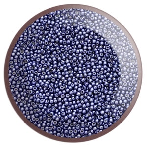 May include: A close-up image of a large quantity of small, round, dark blue beads. The beads are arranged in a random pattern and appear to be made of glass or plastic.