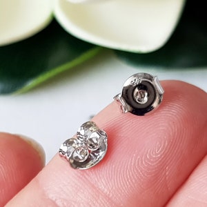 May include: Two silver earring backs, one with the marking "925" on the back.