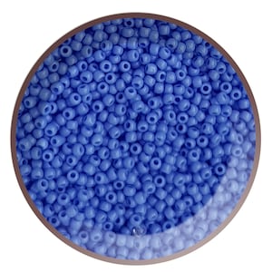 May include: A close-up view of a bowl filled with small, light blue glass beads. The beads are round and have a smooth, glossy finish.