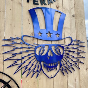 Könnte beinhalten: Blauer Uncle-Sam-Schädel aus Metall mit Blitzen im Haar und einem Zylinder. Der Hut hat weiße Streifen und Sterne.