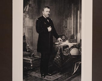 Pode incluir: Uma impressão litográfica em preto e branco com um retrato de Ulysses S. Grant em pé num escritório. Ele veste um casaco escuro e calças. O texto U.S. Grant está impresso abaixo da imagem, com ENGRAVINGS & LITHOS 2025 na parte inferior.