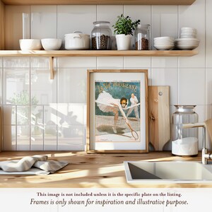 The image is a framed vintage advertisement for a tennis racket, featuring a woman playing tennis. The advertisement is displayed on a wooden shelf above a kitchen counter, with various kitchen items such as bowls, jars, and a cutting board visible in the background.