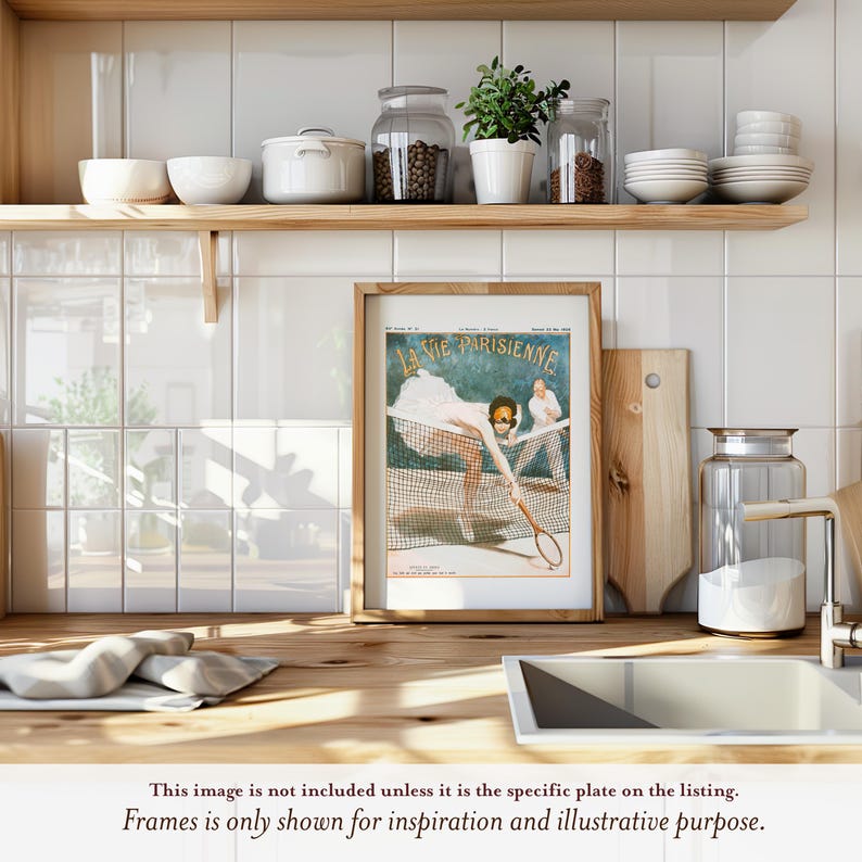 The image is a framed vintage advertisement for a tennis racket, featuring a woman playing tennis. The advertisement is displayed on a wooden shelf above a kitchen counter, with various kitchen items such as bowls, jars, and a cutting board visible in the background.