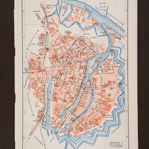 Puede incluir: Un mapa impreso antiguo de Danzig que presenta un sistema de cuadrícula con las letras A a E y los números 1 a 6. El mapa utiliza una paleta de colores naranja claro para las áreas urbanas y azul para las vías fluviales, con etiquetas negras.