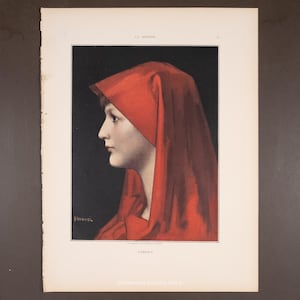 May include: A vintage print depicting a profile portrait of a person in a striking red head covering. The artwork, set against a dark backdrop, shows the subject's face in profile. The print is framed with a white border.