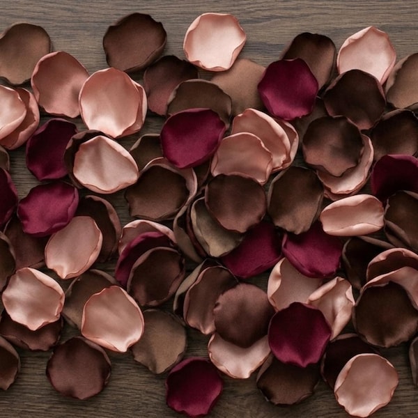May include: A collection of artificial flower petals in a color palette of deep burgundy, dark chocolate brown, and soft blush pink. The petals have a smooth, satin-like finish with rounded, slightly irregular edges, scattered across the frame.