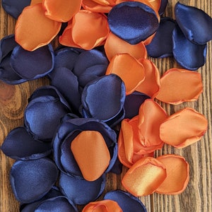 May include: A mix of navy blue and orange satin flower petals. The petals are scattered on a wooden surface.