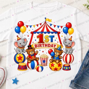 Könnte beinhalten: Weißes T-Shirt mit einem farbenfrohen Zirkus-Design für den ersten Geburtstag. Mit Elefanten, Teddybären, Luftballons und dem Text "1st Birthday" in Rot und Blau.