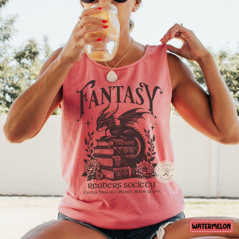 May include: A pink tank top with a black graphic of a dragon sitting on a stack of books. The graphic also includes the text "Fantasy Readers Society" and "Castles, Dragons, Wizards, Heroic Quests".