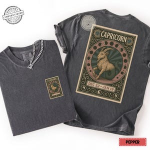 Puede incluir: Dos camisetas grises oscuras con un gr&aacute;fico del signo zodiacal Capricornio. Una camiseta tiene un gr&aacute;fico peque&ntilde;o en la parte delantera, la otra tiene un gr&aacute;fico m&aacute;s grande en la parte posterior. Los gr&aacute;ficos presentan una criatura parecida a una cabra y el texto "CAPRICORNIO" y "22 DIC - 19 ENE".