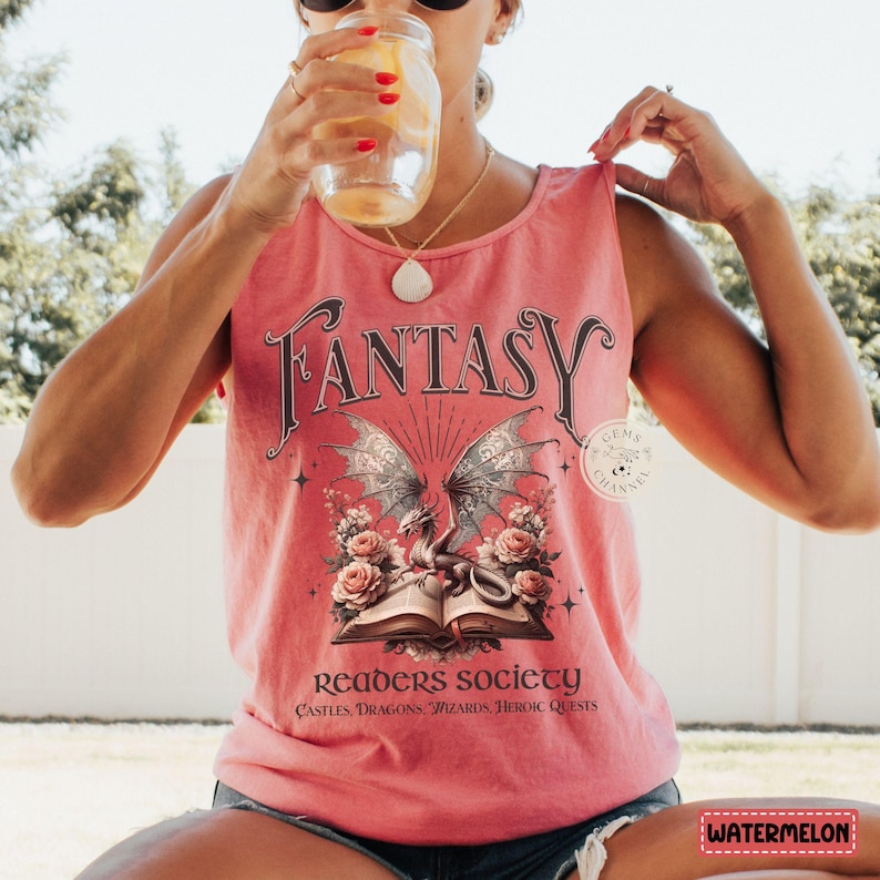 K&ouml;nnte beinhalten: Ein rosafarbenes Tanktop mit einer Grafik eines Drachen und eines Buches. Der Text auf dem Shirt lautet "Fantasy Readers Society Castles, Dragons, Wizards, Heroic Quests".