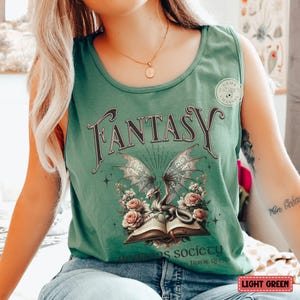 K&ouml;nnte beinhalten: Ein hellgr&uuml;nes Tanktop mit einem grafischen Druck eines Drachen, der ein offenes Buch h&auml;lt. Der Text "Fantasy" ist in Schwarz &uuml;ber dem Drachen gedruckt. Der Text "Where dreams society" ist in Schwarz unter dem Drachen gedruckt.