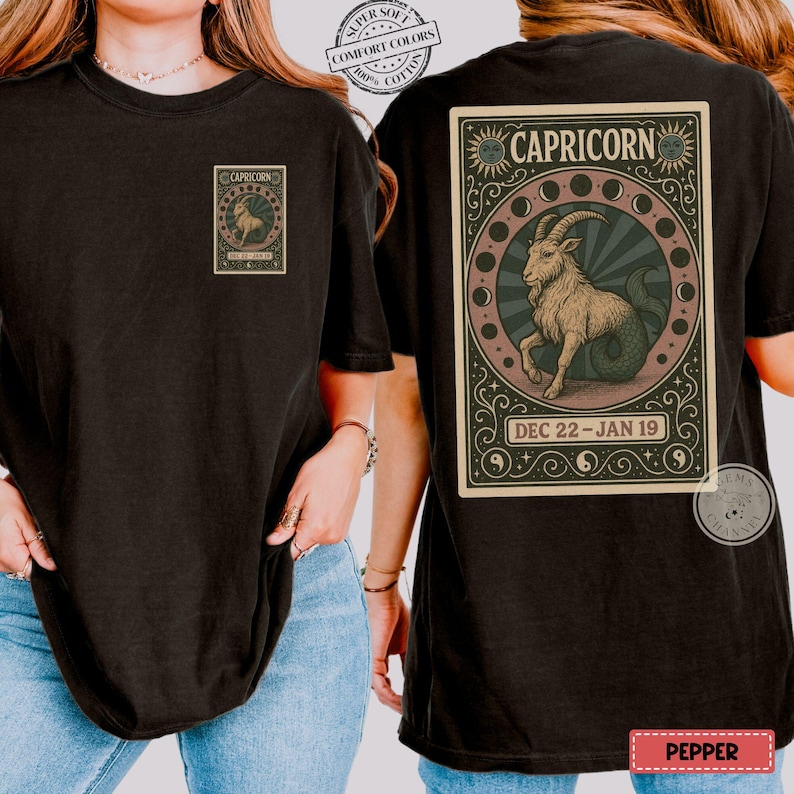 Puede incluir: Camiseta negra con un dise&ntilde;o del signo zodiacal Capricornio. La parte delantera tiene un peque&ntilde;o gr&aacute;fico rectangular, mientras que la parte trasera muestra una ilustraci&oacute;n detallada de una criatura parecida a una cabra dentro de un marco circular, con el texto "CAPRICORNIO" y "22 DIC-19 ENE".
