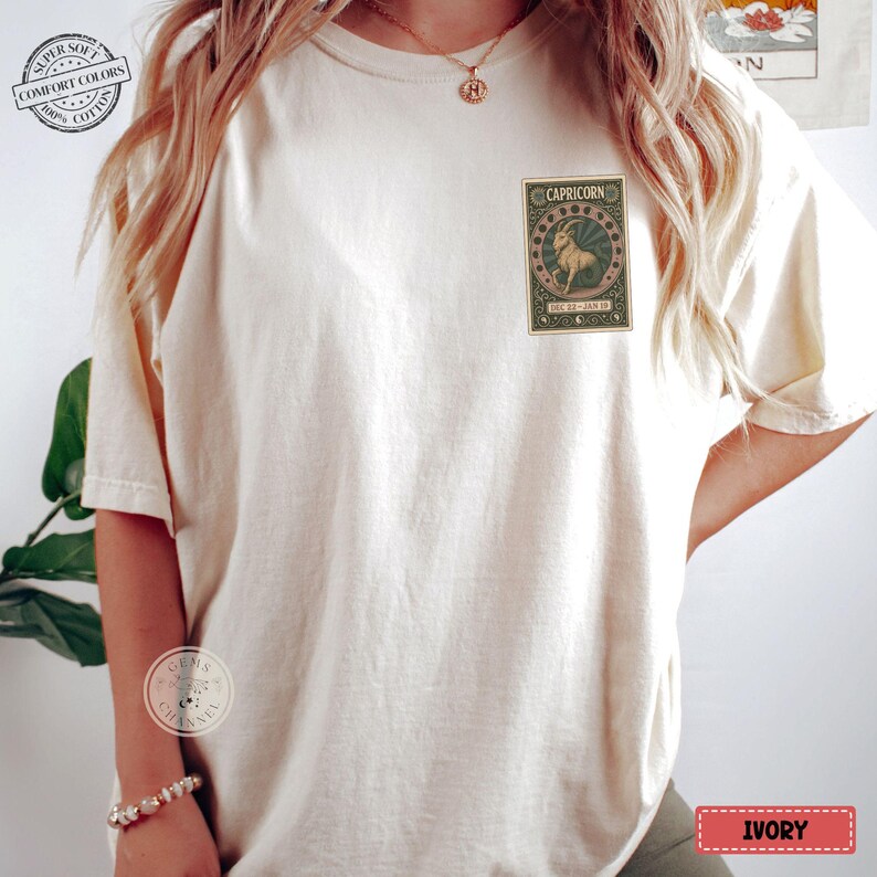 Puede incluir: Camiseta color marfil con un gr&aacute;fico del zodiaco Capricornio en la parte delantera. El gr&aacute;fico presenta una ilustraci&oacute;n de cabra dentro de un marco decorativo. La camiseta tiene un corte holgado y es de algod&oacute;n suave.