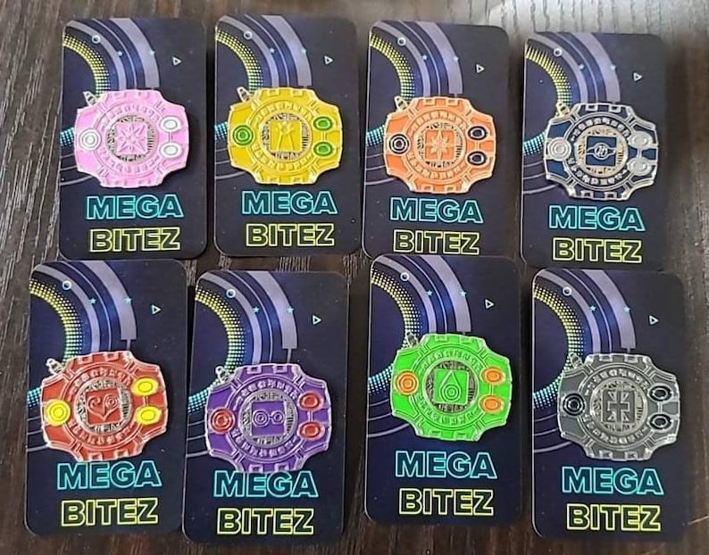 May include: Eight colorful enamel pins featuring a circular design with a central symbol and the text "MEGA BITEZ". The pins are arranged in two rows of four, with each pin on a separate card.