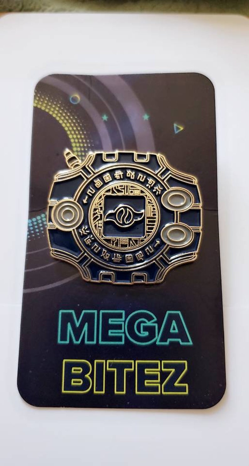 May include: A gold and blue Digimon pin featuring the Digivice with the text "MEGA BITEZ" on the card.