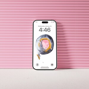 May include: A smartphone with a pink and gray abstract design on the screen. The time is 4:46 and the date is Wednesday, January 24. The phone is on a white surface.