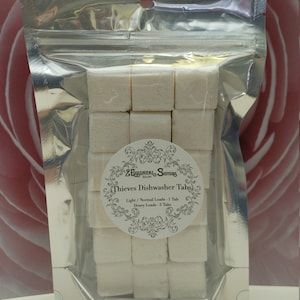 Op de afbeelding: Een zilveren hersluitbare zak gevuld met witte vaatwastabletten. De zak heeft een label met de tekst "ZEssential Sisters Thieves Dishwasher Tabs" en bevat gebruiksaanwijzingen: "Lichte/normale belading - 1 tablet, Zware belading - 2 tabletten".