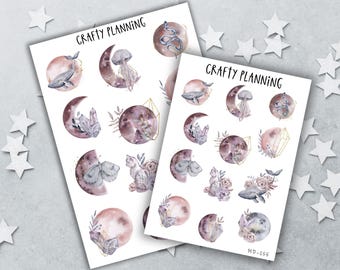 May include: Two white sticker sheets labeled CRAFTY PLANNING featuring watercolor illustrations of moons, whales, jellyfish, snakes, cats, crystals, and flowers in shades of dusty pink, purple, and grey. The designs include geometric gold outlines.