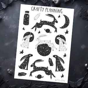 Peut inclure: Une feuille blanche avec des illustrations noires de lapins, d'étoiles, de planètes, de cristaux et d'un croissant de lune. Les mots "Crafty Planning" sont en haut. Le texte "WTC-040" est en bas à droite.