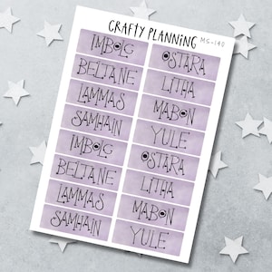 Könnte beinhalten: Ein Bogen mit rechteckigen Aufklebern mit der Aufschrift Crafty Planning MS-140, violettem Aquarellhintergrund und schwarzem Text, der heidnische Feiertage wie Imbolc, Beltane, Lammas, Samhain, Ostara, Litha, Mabon und Yule in Schriftart auflistet.