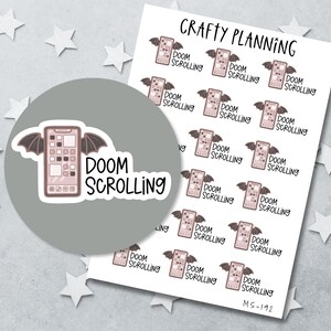May include: A sheet of Crafty Planning stickers featuring a pink smartphone with bat wings and the text Doom Scrolling. The design includes multiple repeating icons of the phone with wings and the words Doom Scrolling in a black handwritten font.
