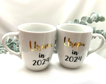 Tasse Uroma in 2025 und Tasse Uropa in 2025, Porzellantassen mit goldener Schrift im Handlettering-Stil, Schwangerschaft verkünden