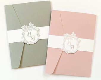 Ejemplo de invitación de boda de lujo de 5x7 con marco ornamental y bolsillo desplegable con banda de vientre troquelada en tonos rubor, salvia y varios colores.