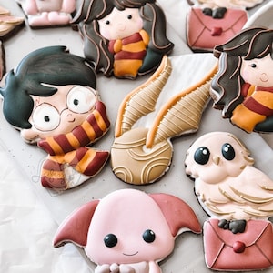 Peut inclure: Un ensemble de neuf biscuits en sucre sur le thème d'Harry Potter. Les biscuits sont décorés de divers personnages et symboles de l'univers d'Harry Potter, notamment Harry Potter, Hermione Granger, Ron Weasley, Hedwige la chouette, un vif d'or et un elfe de maison. Les biscuits sont tous de formes et de tailles différentes, et ils sont tous décorés de détails complexes.
