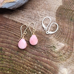 May include: A pair of pink teardrop-shaped earrings with gold wire and silver ear wires.