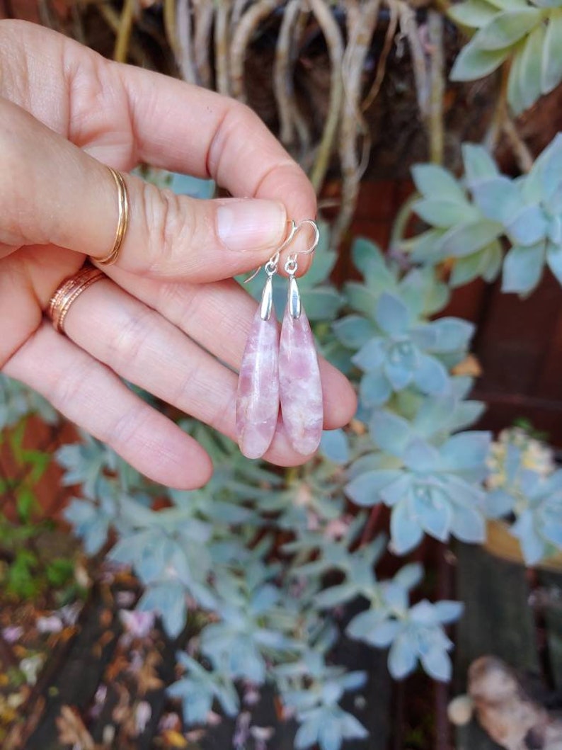 Op de afbeelding: Een paar oorhangers met roze en witte traanvormige stenen. De stenen zijn gezet in zilver.