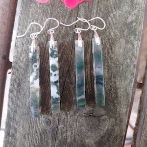 May include: Four pairs of dangle earrings with silver hooks and green and white agate stone pendants. The stones are rectangular and have a natural, organic pattern.