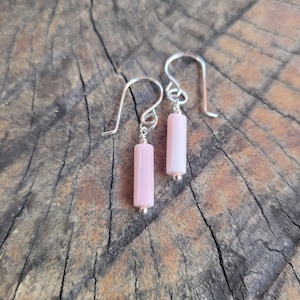 Può includere: Un paio di orecchini d'argento con pietre rettangolari rosa che pendono dai ganci.