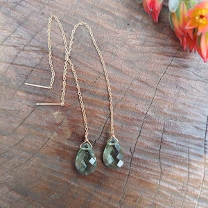 Puede incluir: Un par de pendientes largos de cadena dorada con colgantes de piedra preciosa verde en forma de lágrima.