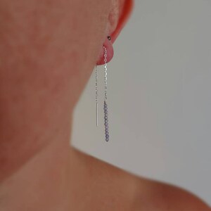 May include: Silver chain earrings with small purple beads hanging from the bottom.