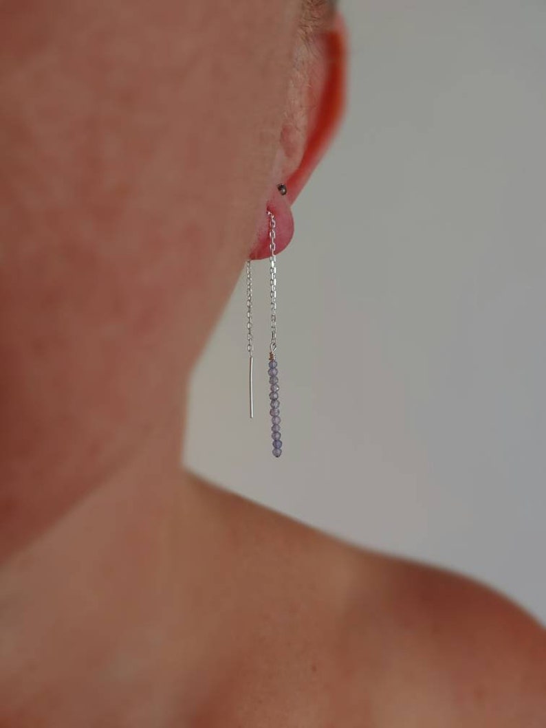 May include: Silver chain earrings with small purple beads hanging from the bottom.