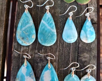 Könnte beinhalten: Ein Set mit sechs tropfenförmigen Ohrringen aus blauem und weißem Achat. Die Ohrringe sind silberfarben und haben einen Hakenverschluss.