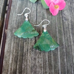 Può includere: Un paio di orecchini in giada verde con un design a forma di ventaglio. Gli orecchini sono in argento e hanno un design delicato e intricato.
