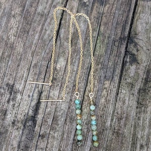 May include: A pair of gold chain earrings with turquoise beads. The earrings are long and dangle.