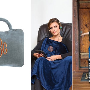 May include: A gray travel pillow with a monogrammed design. The pillow has a handle and is made of soft, plush fabric. The monogram is in orange thread and reads "ABC".