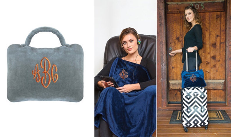 May include: A gray travel pillow with a monogrammed design. The pillow has a handle and is made of soft, plush fabric. The monogram is in orange thread and reads "ABC".