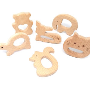 May include: Six wooden teethers shaped like animals, including a bear, deer, elephant, turtle, squirrel, and cat. The teethers are made of natural wood and have a smooth, rounded surface.
