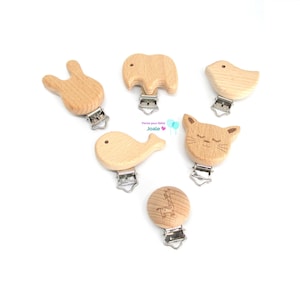 Peut inclure: Ensemble de six  mordeurs pour bébés en bois avec différents motifs d'animaux, dont un lapin, un éléphant, un oiseau, une baleine, un chat et une girafe. Chaque  mordeur est doté d'un clip argenté pour l'attacher aux vêtements.