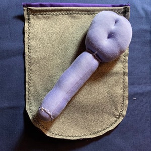 May include: A purple fabric pouch with a purple and gray fabric lining. A purple fabric stuffed toy shaped like a long, thin, rounded object is inside the pouch.