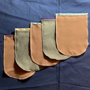 May include: Five fabric pouches in different colors and sizes, with a light brown, gray, and brown color scheme. The pouches are lined with a contrasting color fabric and have a decorative stitch around the edges.
