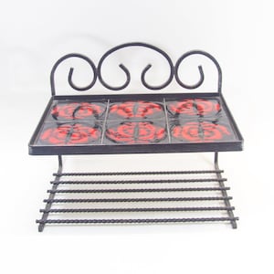 Peut inclure: Une étagère en métal noir avec un dessus décoratif et une étagère inférieure avec une grille en fil de fer. L'étagère supérieure comporte quatre carreaux en céramique rouge et noir avec un motif floral.