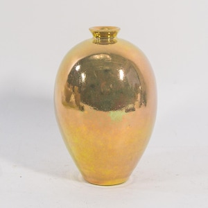 Könnte beinhalten: Eine birnenförmige, schillernde Vase mit goldgelbem Finish. Die Keramikvase hat einen schmalen Hals und einen abgerundeten Körper. Die Oberfläche reflektiert das Licht und erzeugt einen schimmernden Effekt. Die Vase ist ein dekorativer Gegenstand.