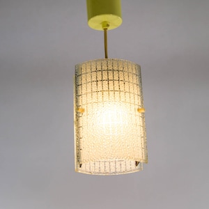 May include: A vintage pendant light with a clear, textured glass shade and a yellow metal canopy.